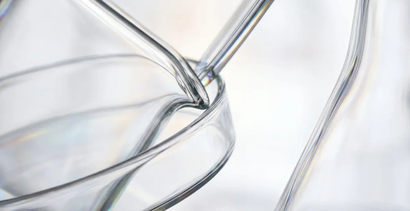 Vue macro sur des surfaces en verre de laboratoire avec reflets subtils évoquant les technologies de diagnostic avancées